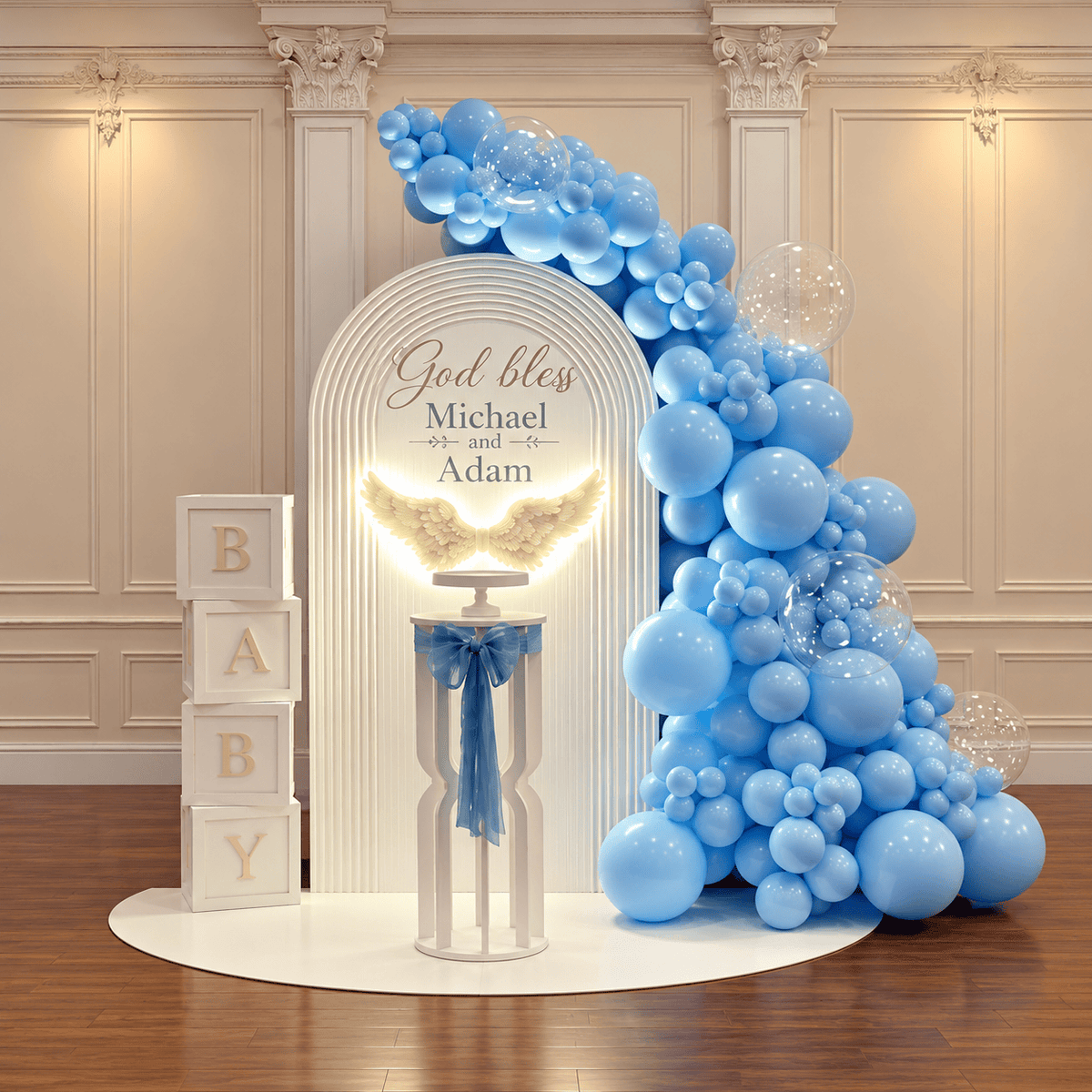 White baptism arch with personalized lettering, illuminated angel wings, blue balloons, clear bubbles, BABY blocks, and a cake pedestal.
