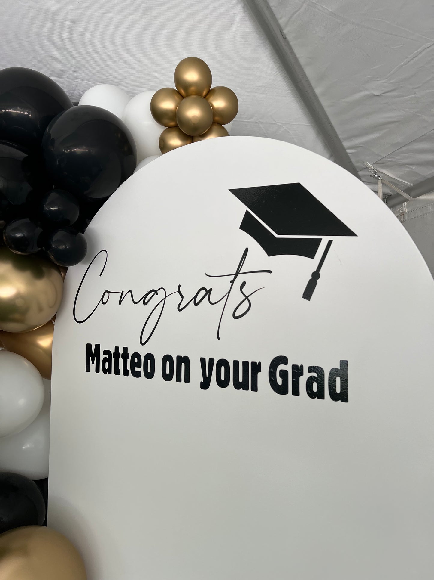 White balloon with 'Congrats Matteo on your Grad' text and graduation cap symbol, surrounded by balloons.