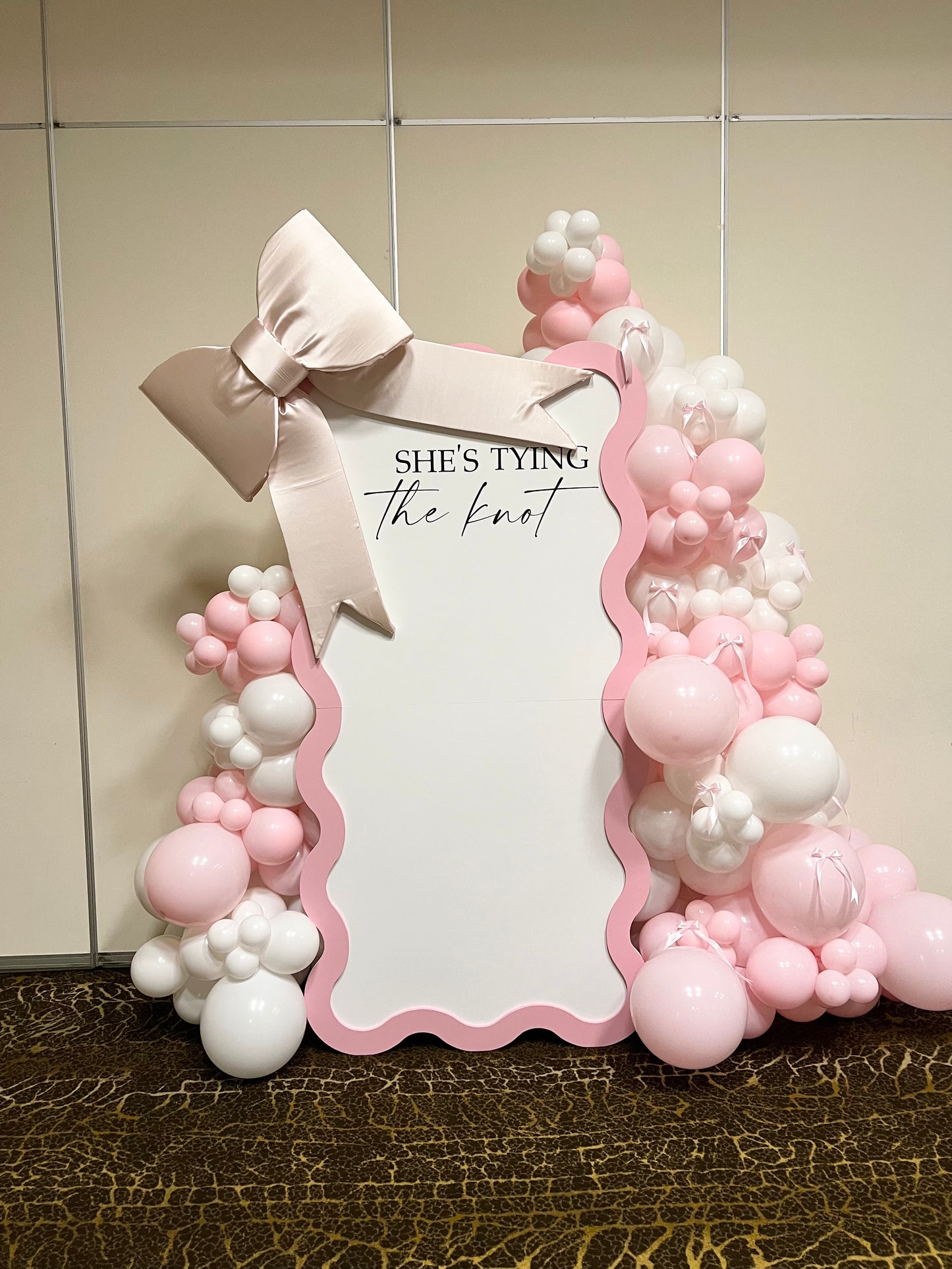 bridal shower wavy backdrop with pink white balloon garlands and bows