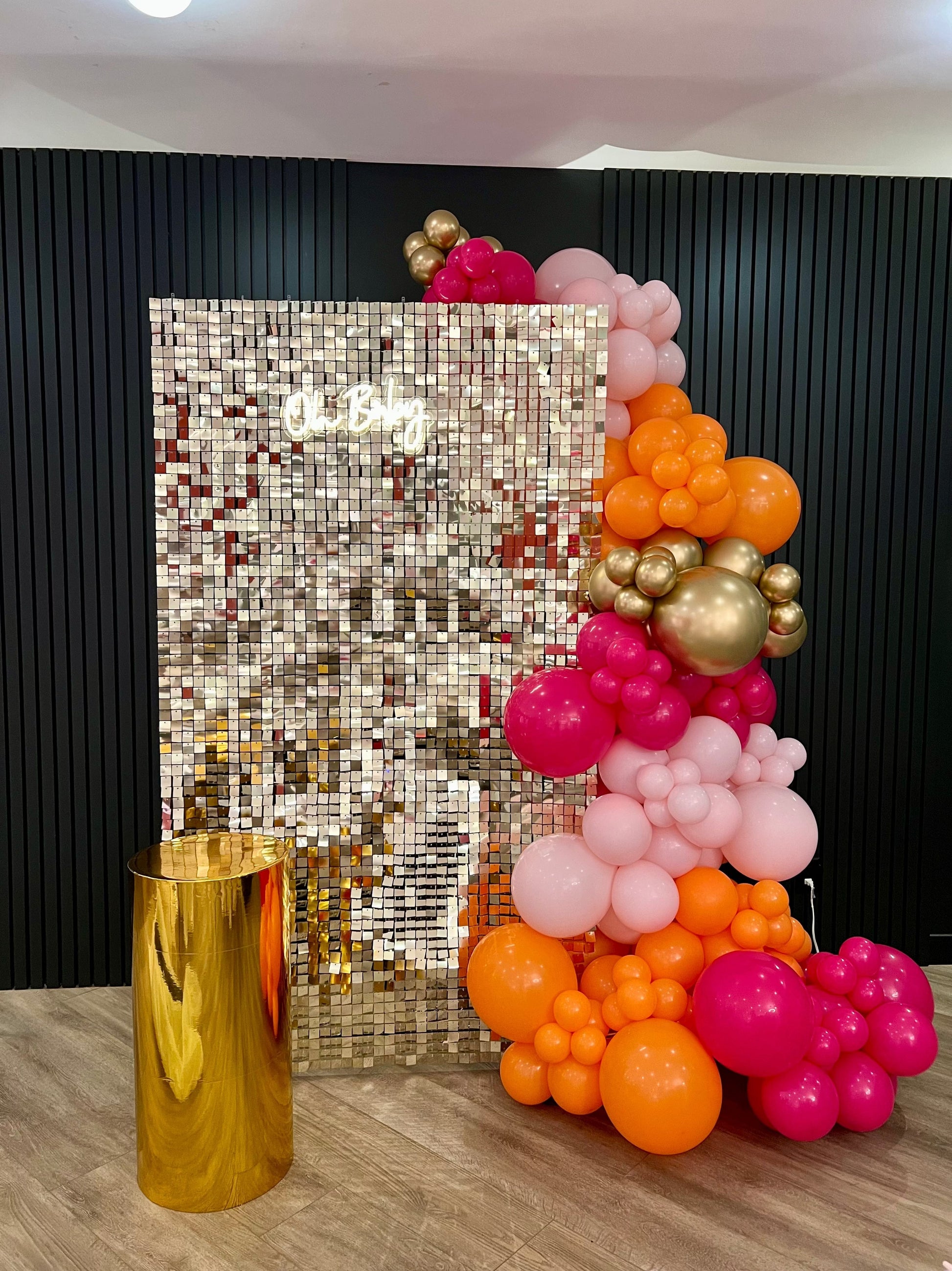 Light gold shimmer wall with Oh Baby neon sign, gold cake table, and balloon garland for baby shower décor