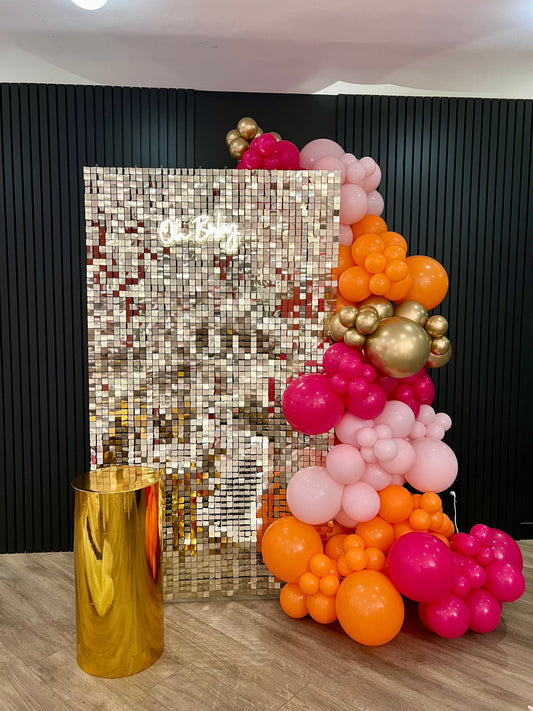 Light gold shimmer wall with Oh Baby neon sign, gold cake table, and balloon garland for baby shower décor