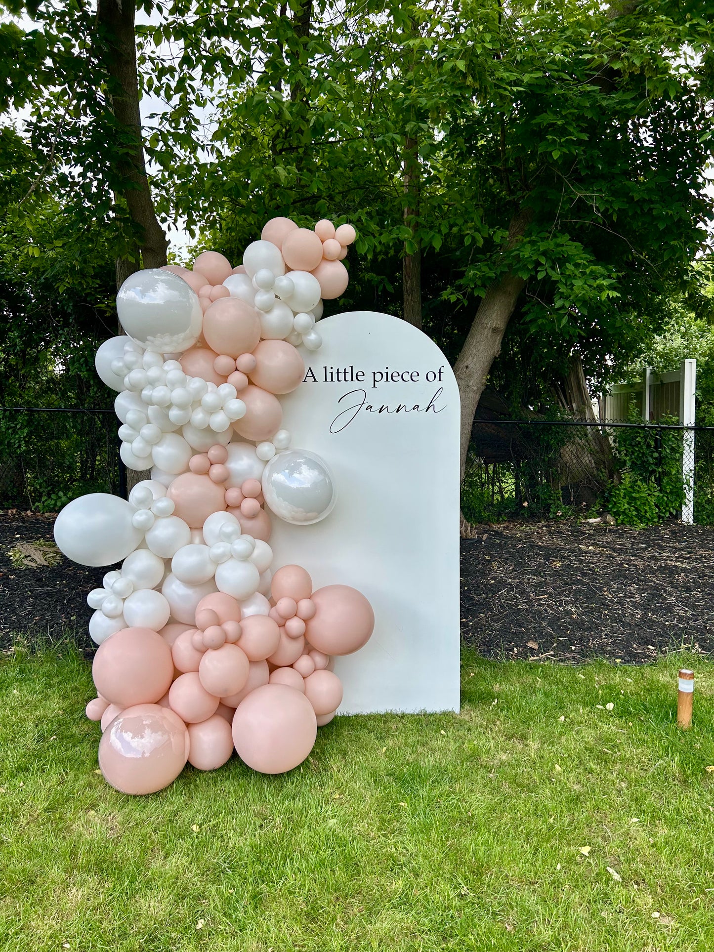 Blush baby shower setup with white oval backdrop and pearl balloon garland