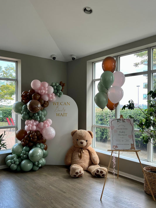 Teddy bear baby shower backdrop with white oval wall, balloon garland in green beige and dusty rose tones, teddy bear & welcome sign with helium balloons