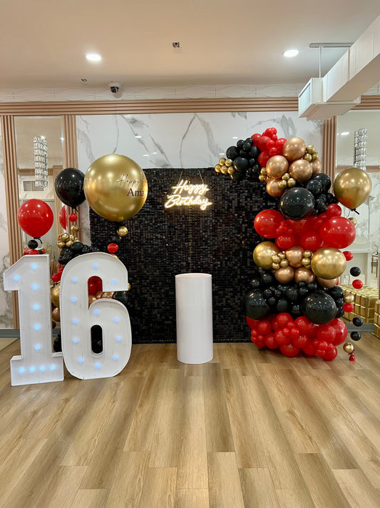 Black shimmer wall 8x8 with balloon garlands, Happy Birthday neon sign, marquee numbers 16, cake table, and helium balloon arrangement