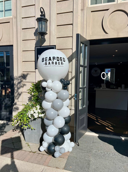 Branded balloon column with large custom logo balloon on top at storefront.