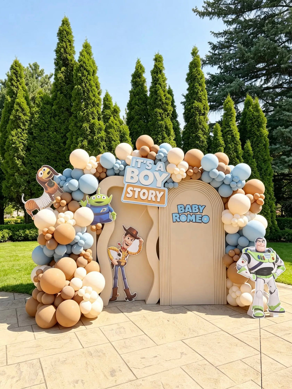 Toy Story baby shower backdrop with blue, cream, and caramel balloons, an “It’s a Boy Story” sign, and character cutouts.