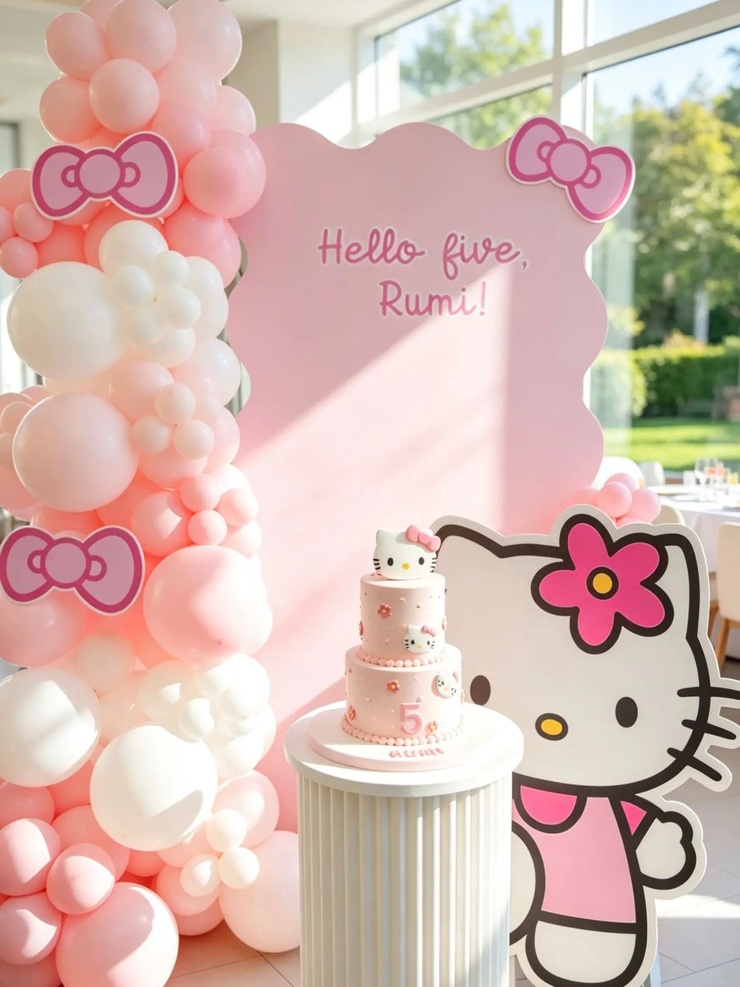 Hello Kitty 5th birthday backdrop with a pink wavy backdrop, blush pink and white balloon garland, Hello Kitty cutout and cake pedestal.