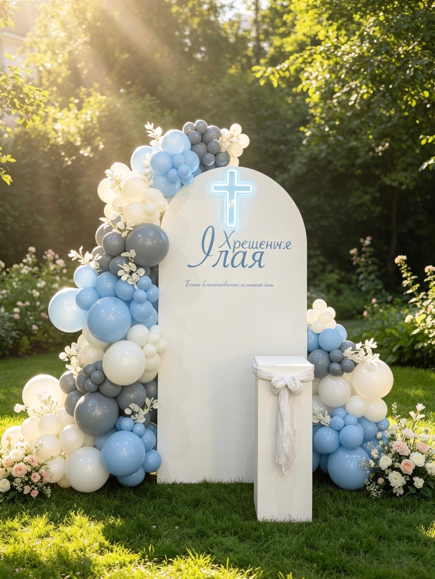 White baptism backdrop with a glowing blue cross, blue and white balloon garlands, floral accents and a matching white pedestal stand.