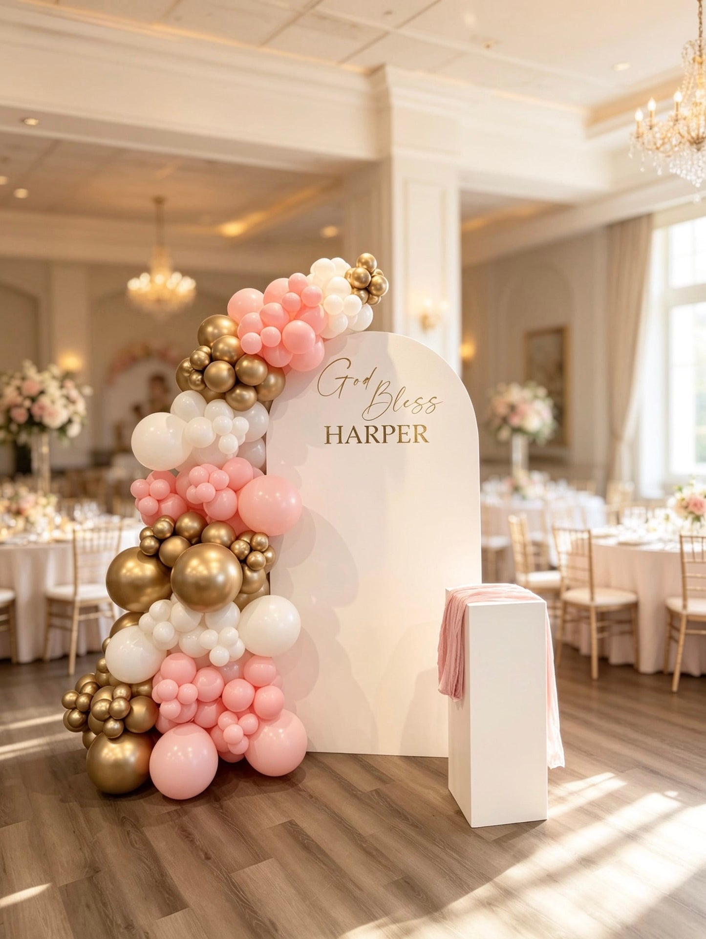 White communion backdrop with pink, white and gold balloon garland and matching pedestal stand