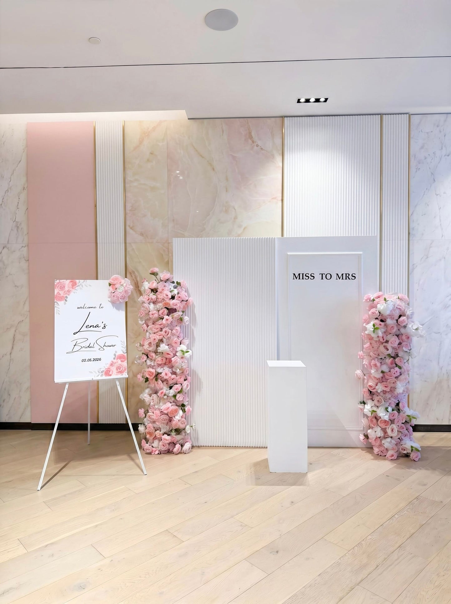 Luxury bridal shower backdrop with blush floral columns and modern white panels.