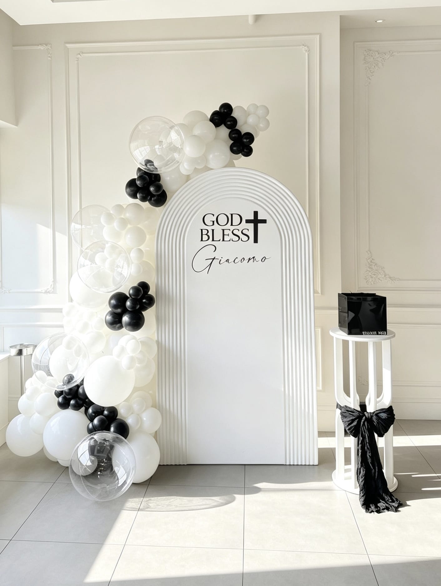 White ripple arch communion backdrop with black and white balloon garland, clear bubble balloons and pedestal stand