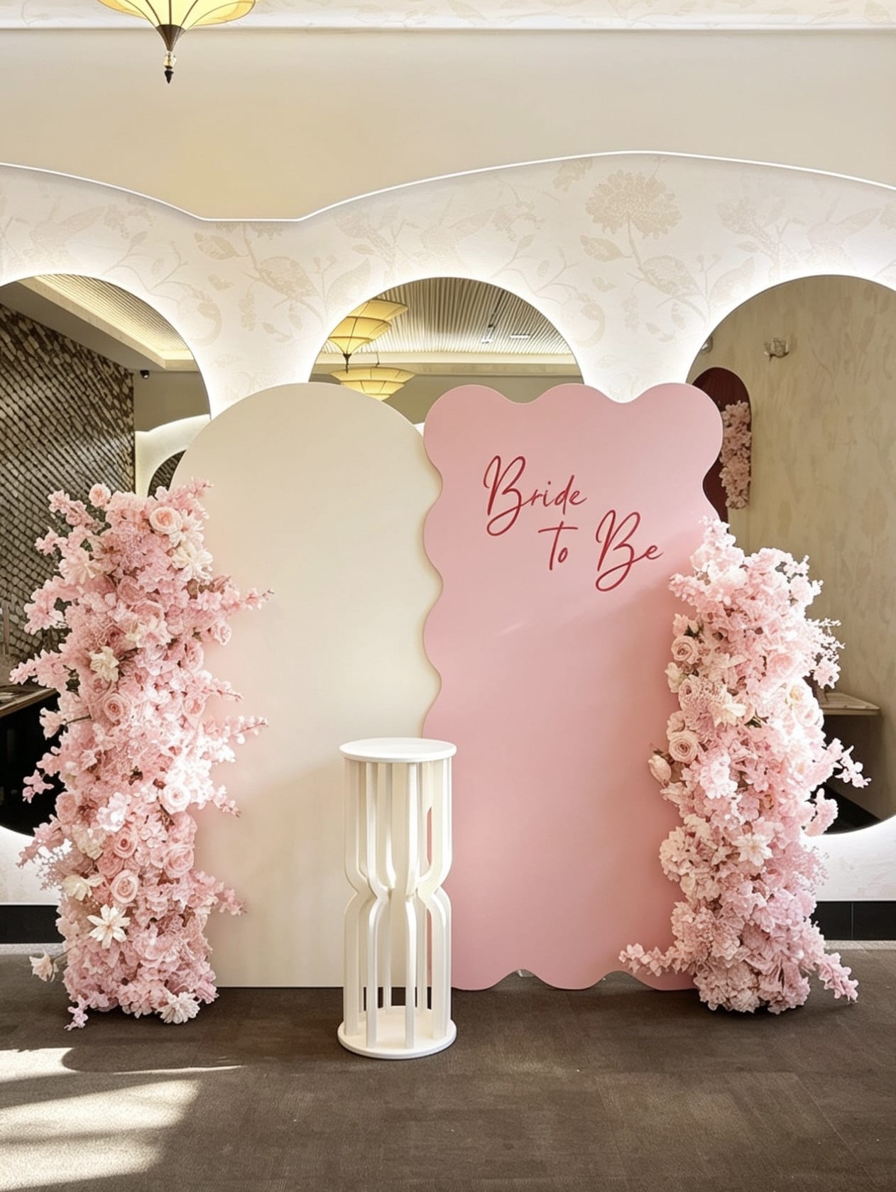 Blush pink bridal shower backdrop with layered panels and floral columns.