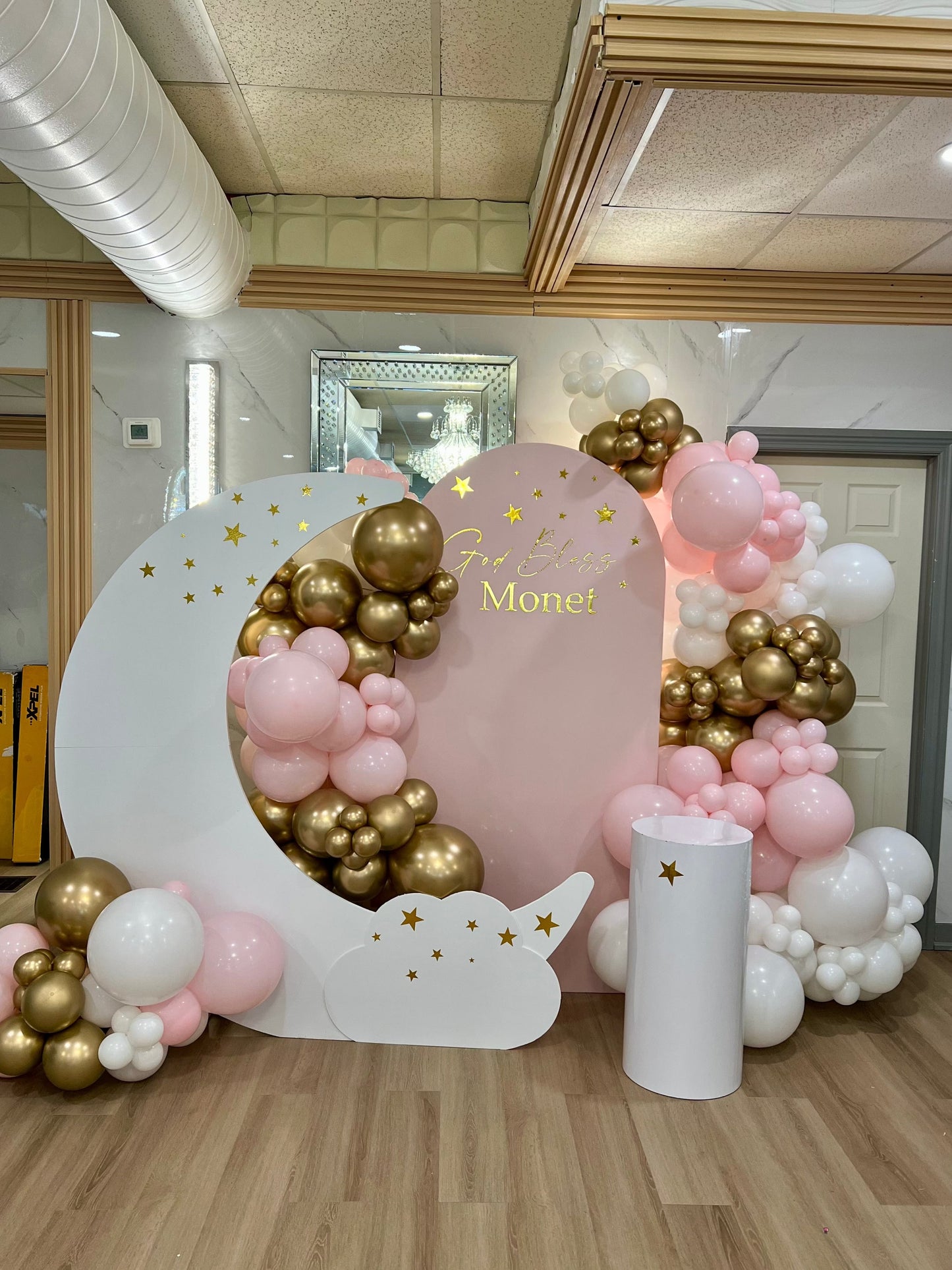 Baptism setup with pink moon backdrop, balloon garlands and custom name.
