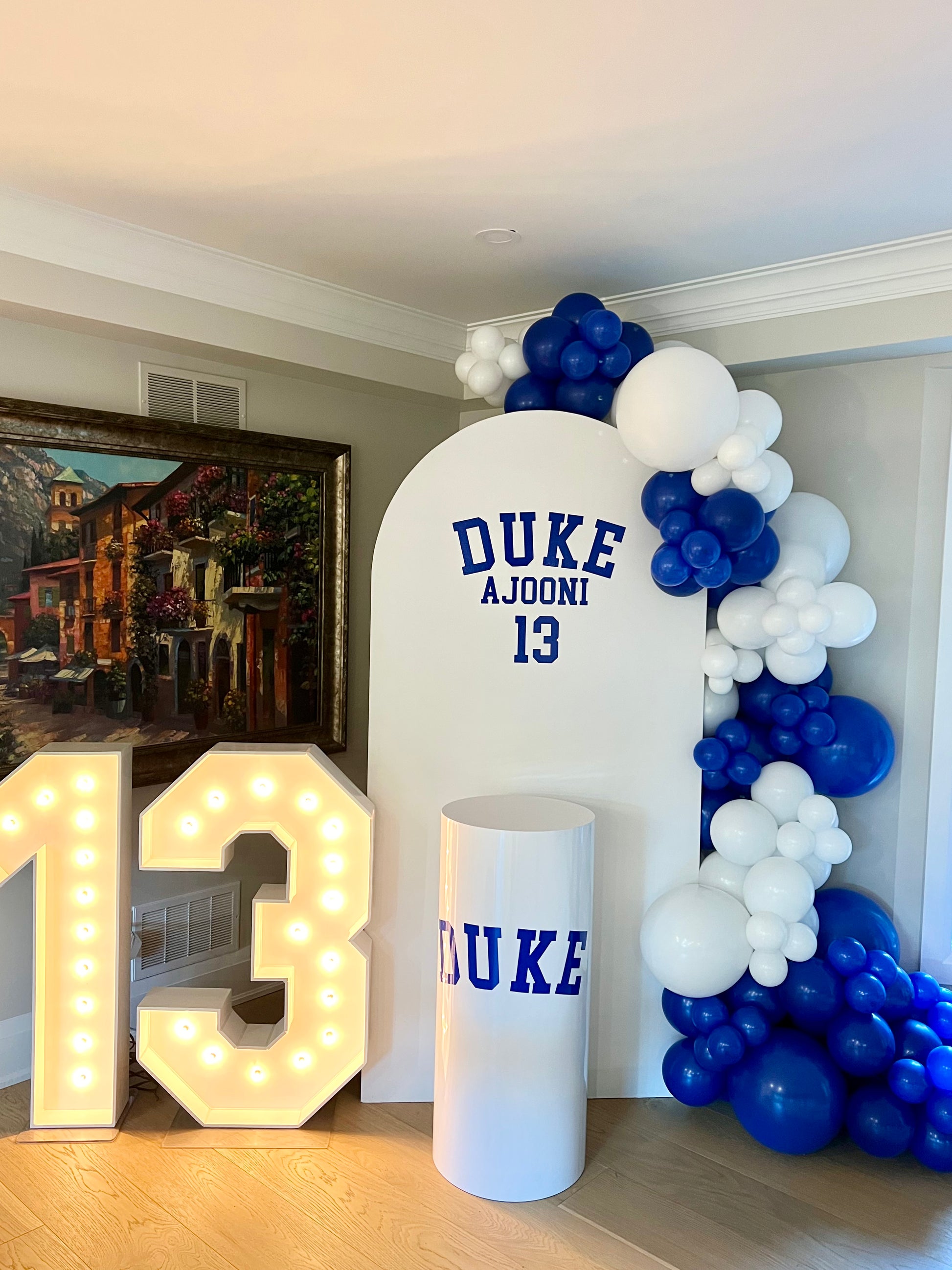 blue sports themed birthday backdrop with balloon garland and marquee numbers
