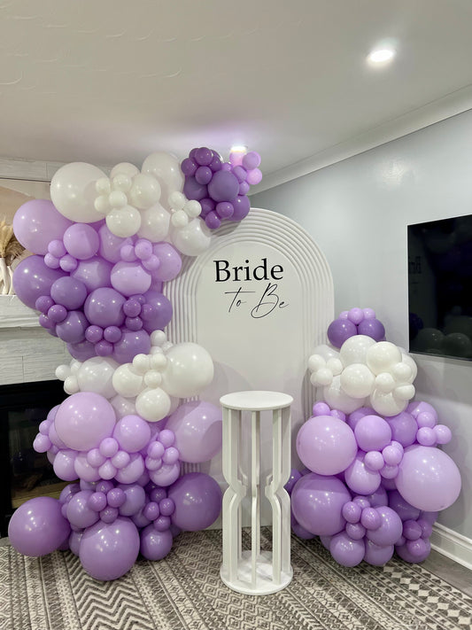 lavender bridal shower backdrop with ribbed white wall and balloon garlands

