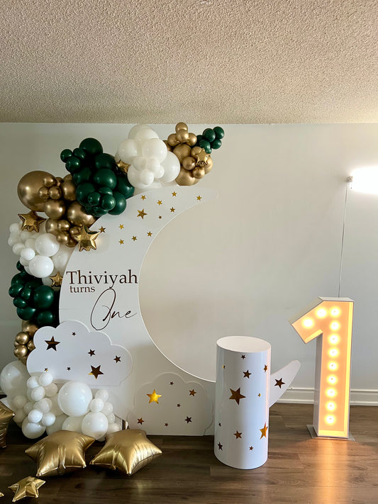 first birthday moon balloon backdrop with emerald green gold garland number 1 and star decorations
