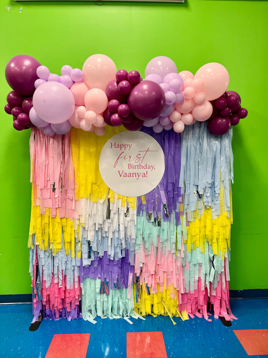 colorful fringe backdrop with balloon garland and custom sign for birthday