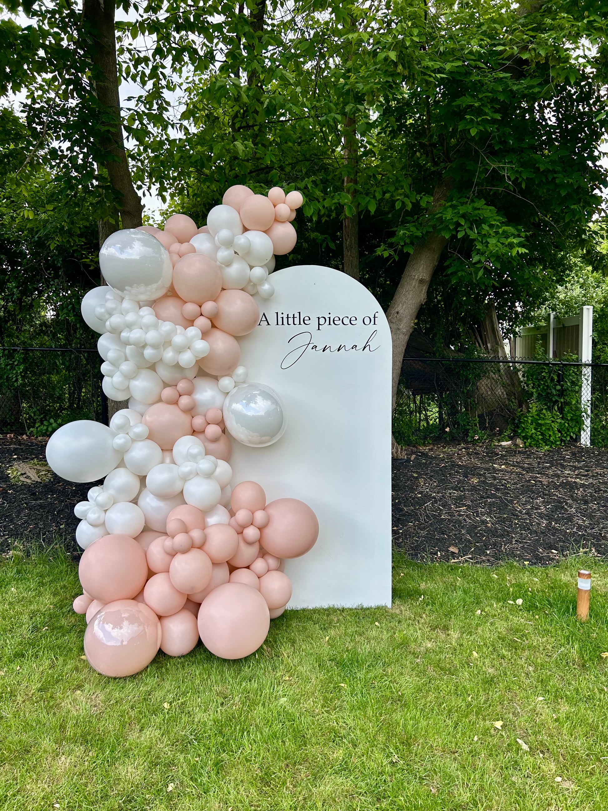 Blush baby shower setup with white oval backdrop and pearl balloon garland
