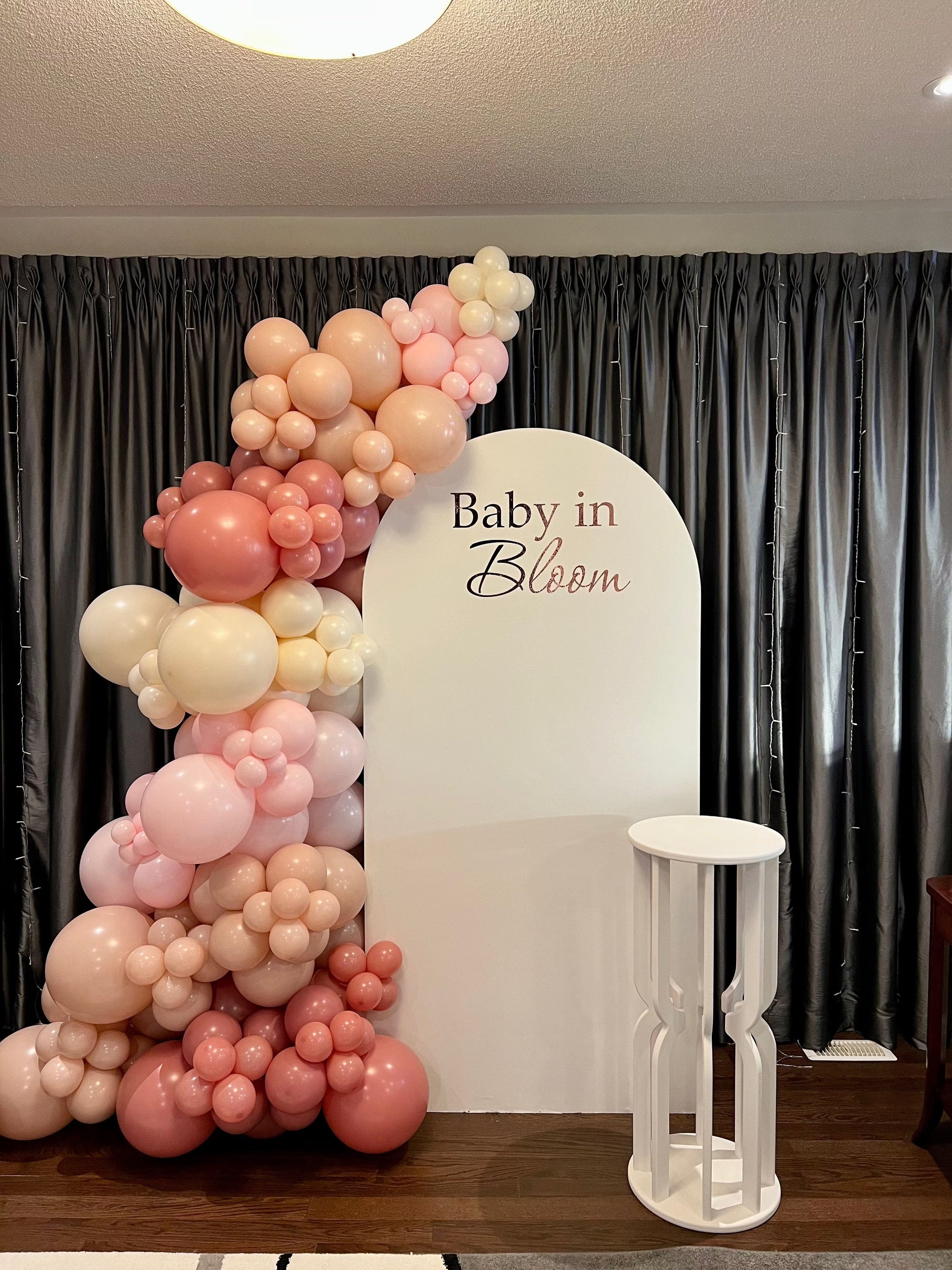 Blush Baby in Bloom backdrop with white oval wall, pink beige and white balloon garland, and matching cake table

