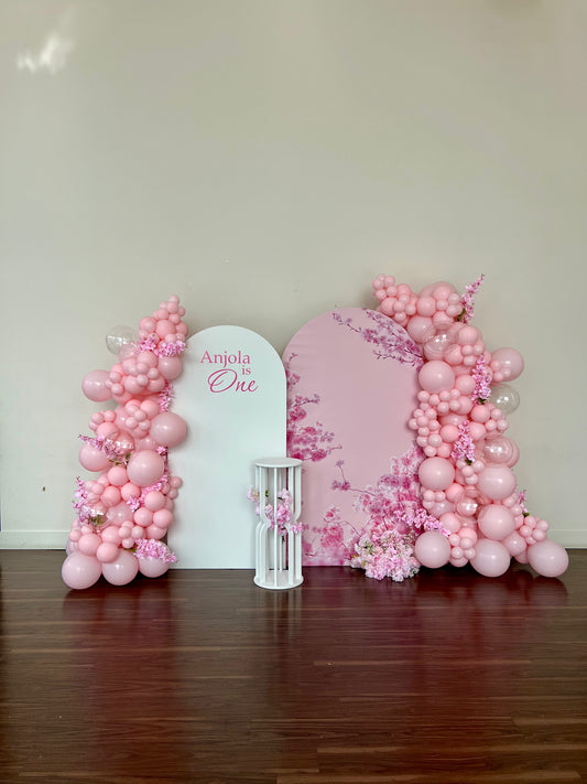 cherry blossom first birthday balloon backdrop with pink garlands and floral decor
