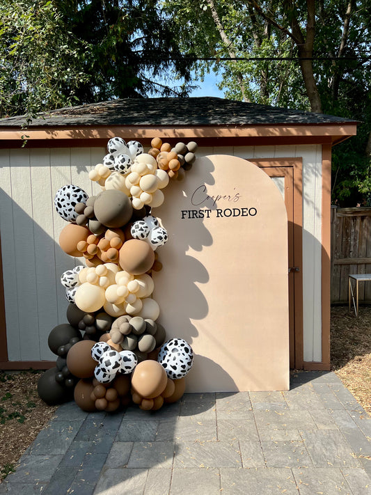 first rodeo 1st birthday balloon backdrop with cow print balloons and brown garland
