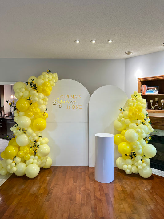 lemon first birthday balloon backdrop with yellow garlands and lemon decorations
