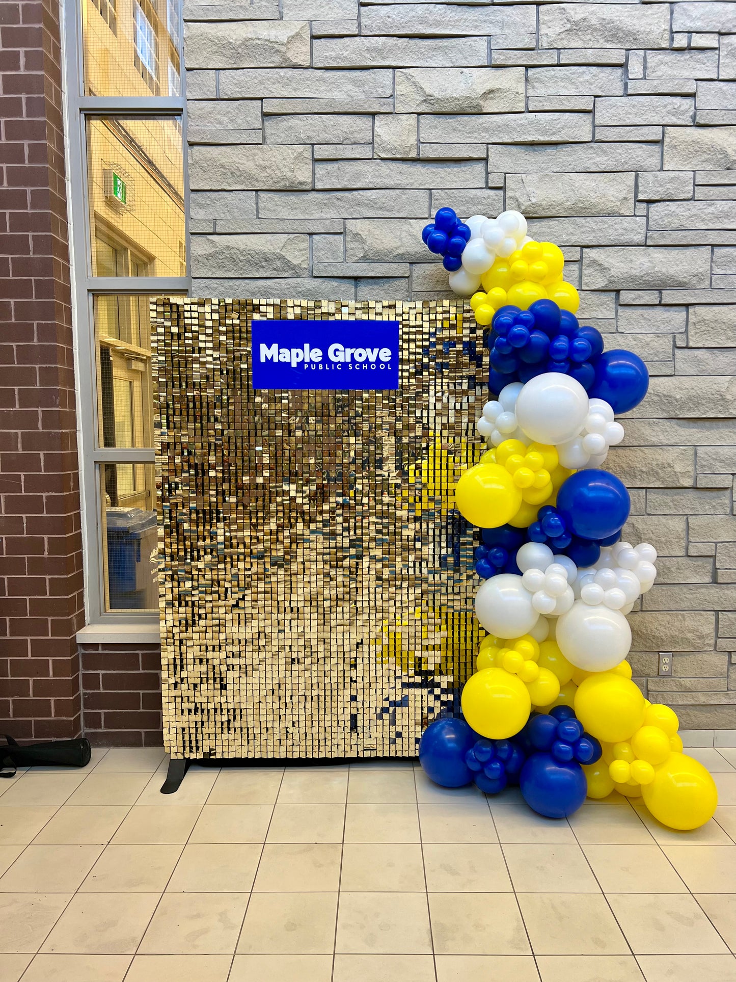 gold shimmer wall backdrop with school sign and balloon garland
