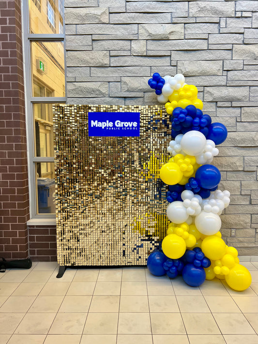 gold shimmer wall backdrop with school sign and balloon garland
