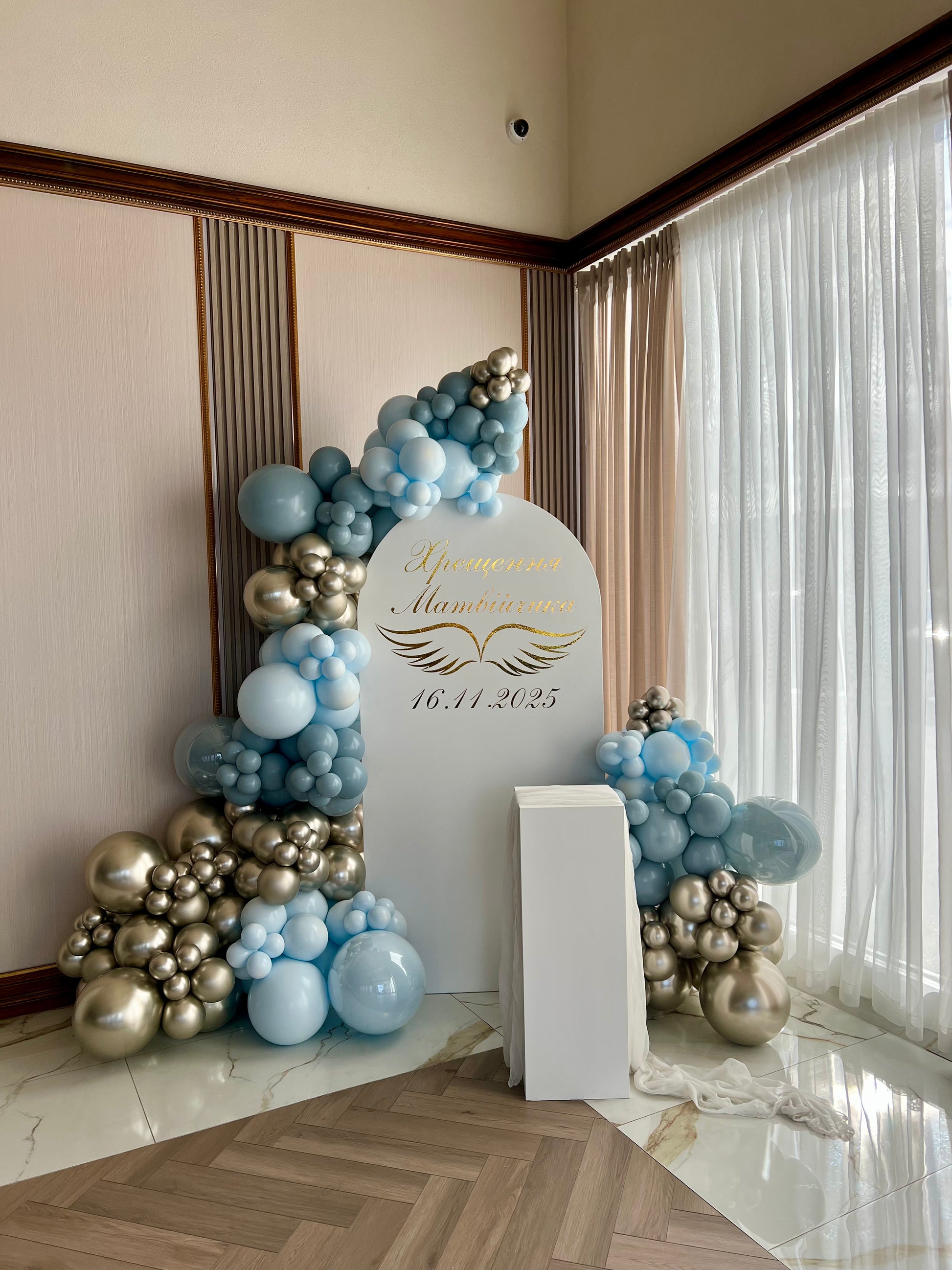 christening balloon backdrop with white arch gold and blue garlands
