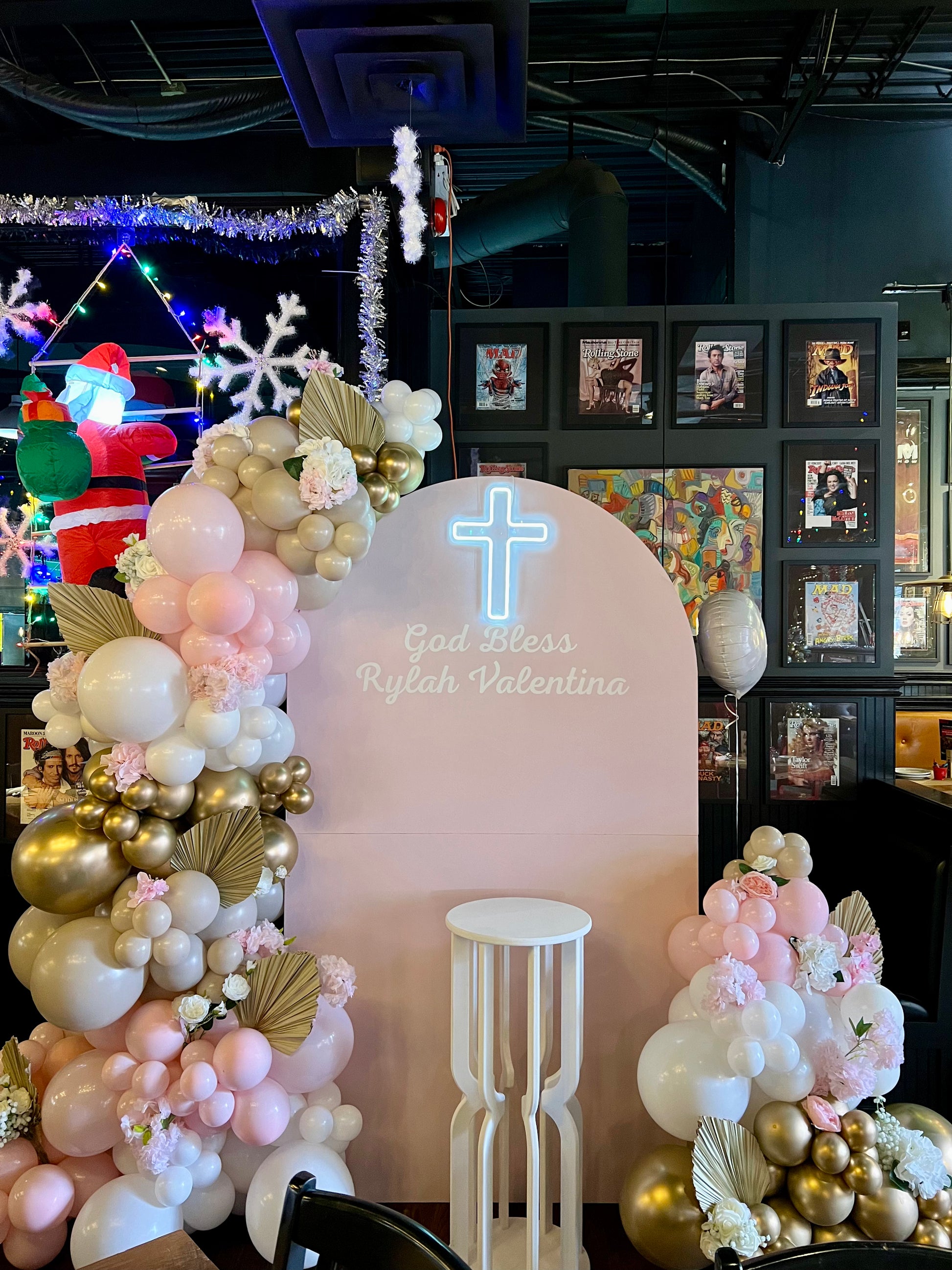 balloon backdrop with pink garlands floral accents and neon cross
