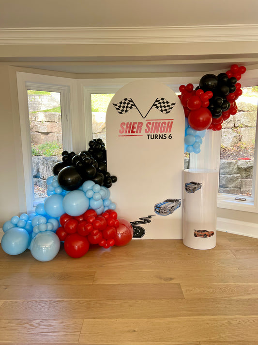 racing birthday balloon backdrop with black red blue garland and car theme
