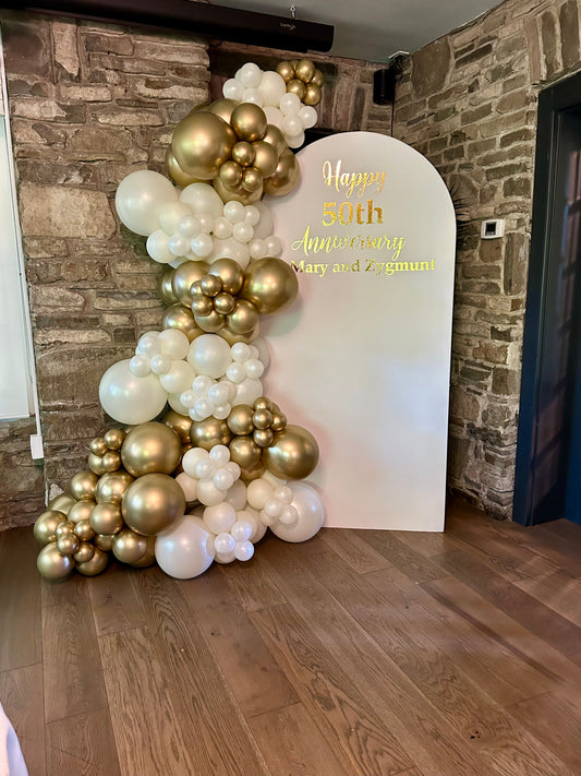 50th anniversary white arch backdrop with gold pearl balloon garland
