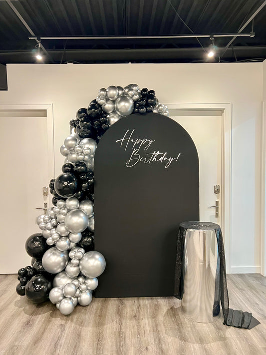 black and silver luxury birthday backdrop with chrome balloon garland and mirrored pedestal