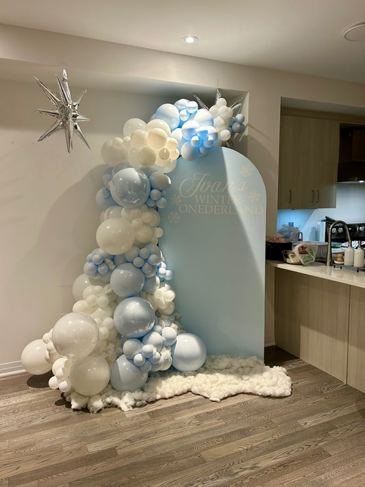 winter wonderland first birthday balloon backdrop with blue and white garland
