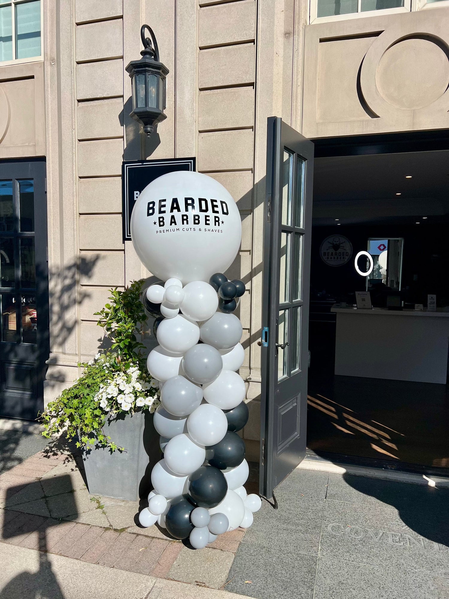 Branded balloon column with large custom logo balloon on top at storefront.
