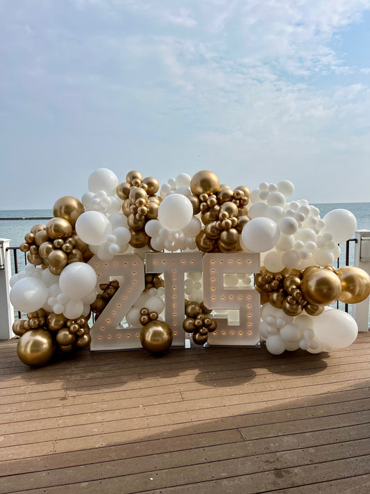 Custom three letter marquee setup with white and gold balloon garland
