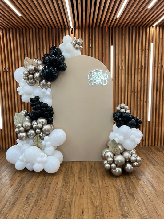 Graduation balloon backdrop with neon congrats grad sign and black gold garlands