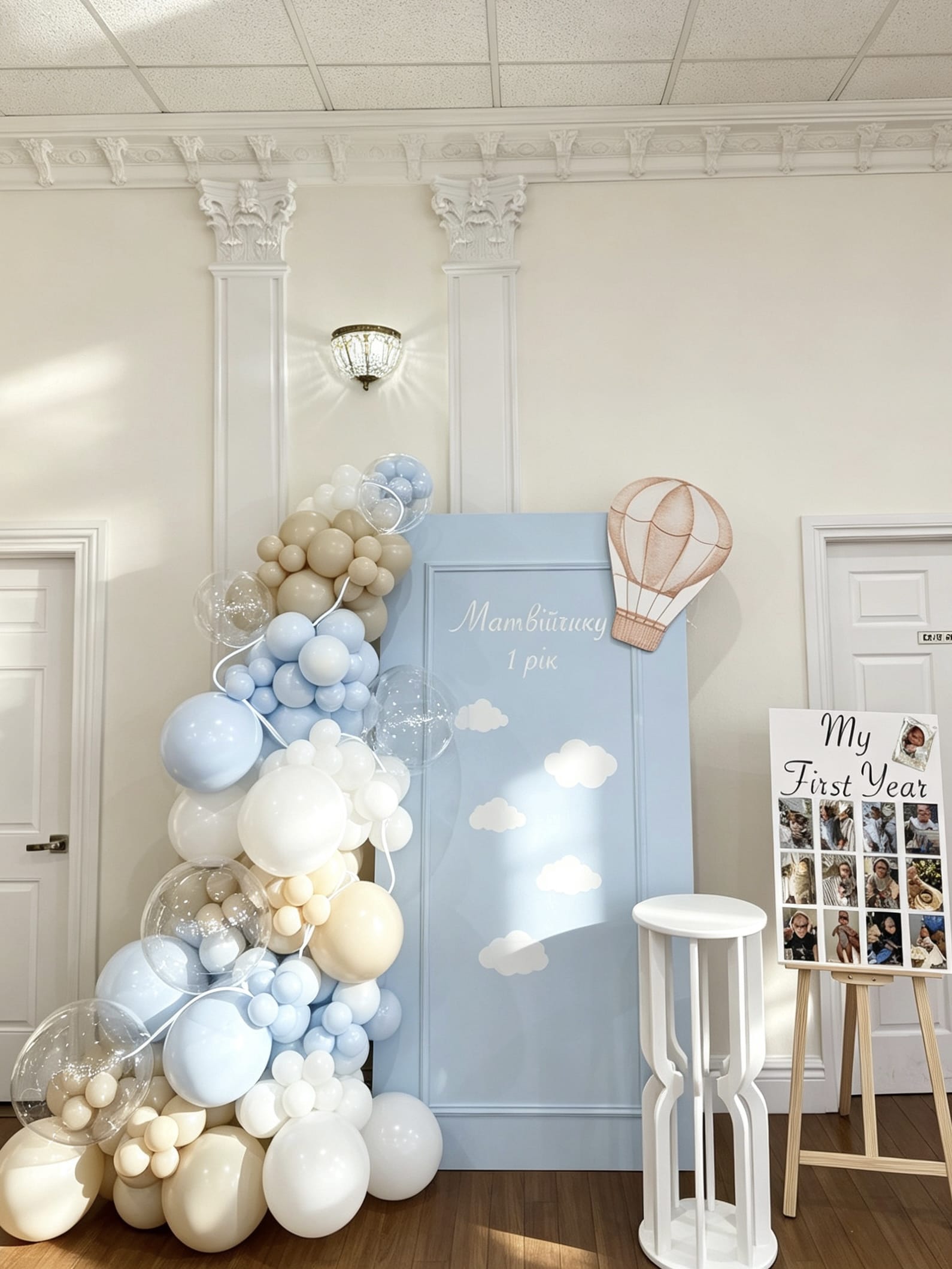 Blue first birthday backdrop with hot air balloon accent and pastel balloon garland