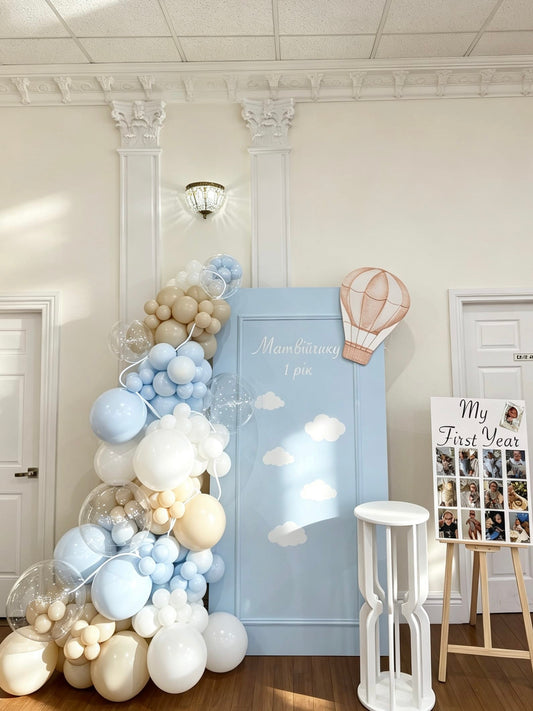 Blue first birthday backdrop with hot air balloon accent and pastel balloon garland