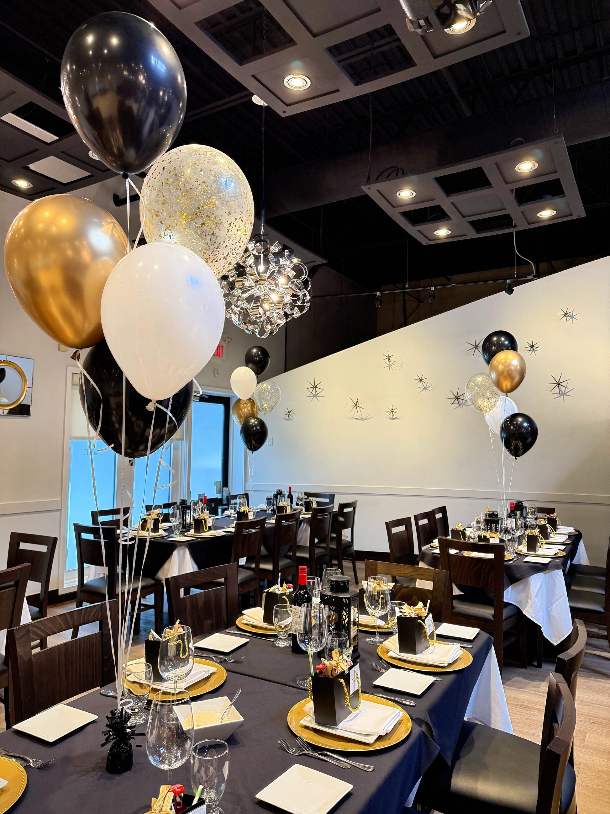 Five helium balloon centrepiece with black, gold, white, and confetti balloons for elegant dinner events.