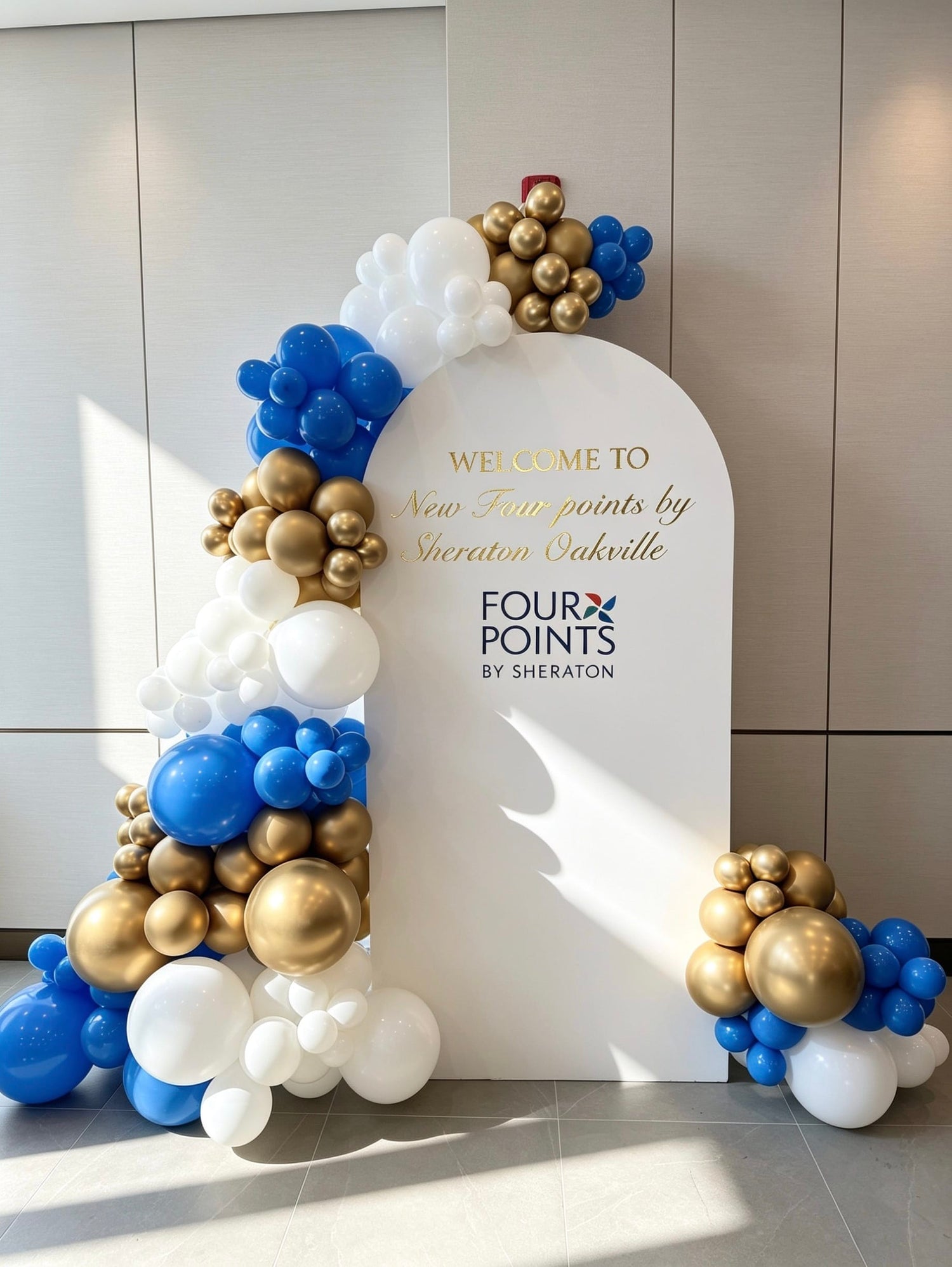 white full arch corporate backdrop with blue white and gold balloon garland
