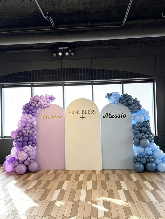 Three-panel twins baptism backdrop with custom names, God Bless sign and lavender and blue balloon garlands