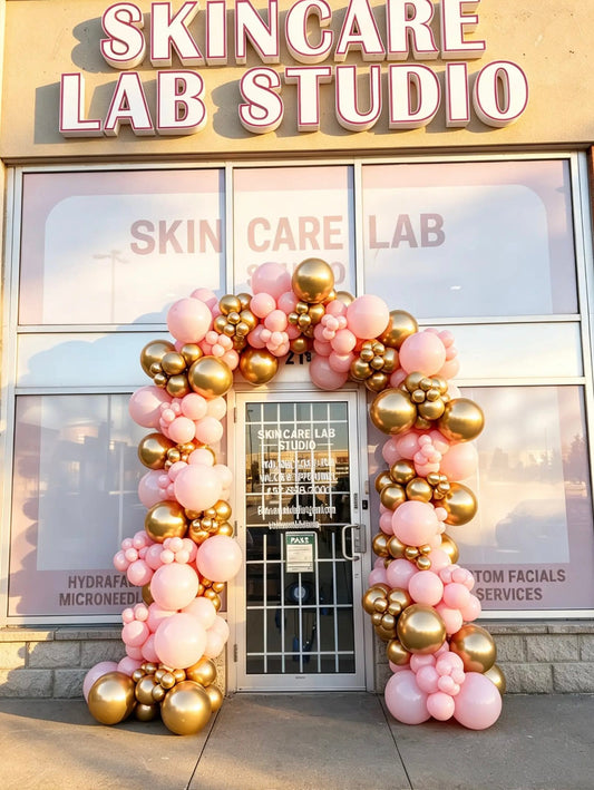 20 ft pink and gold organic balloon arch installed around a storefront entrance for a business event.