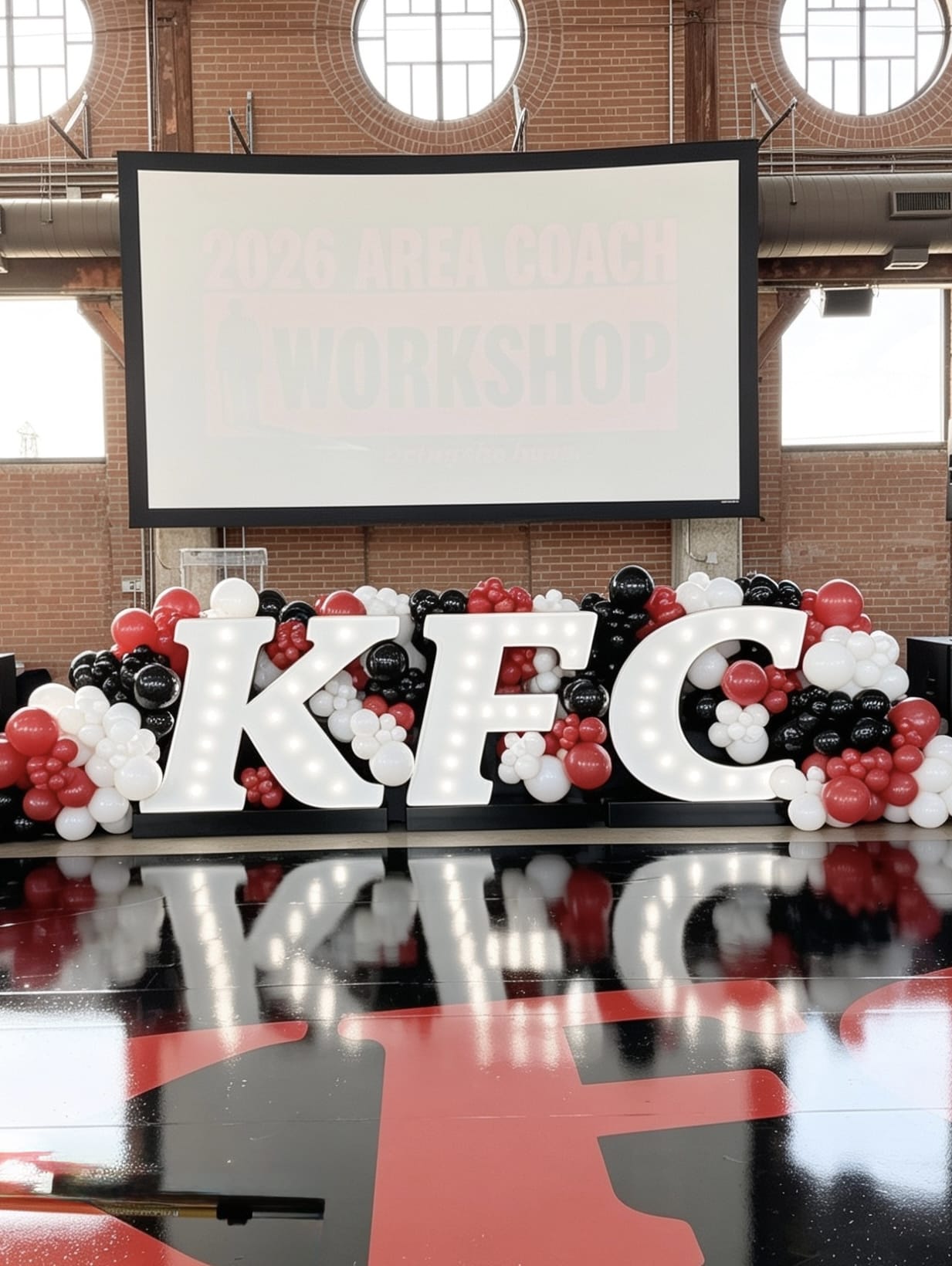 Illuminated KFC marquee letters with red, black and white organic balloon garland at a corporate event