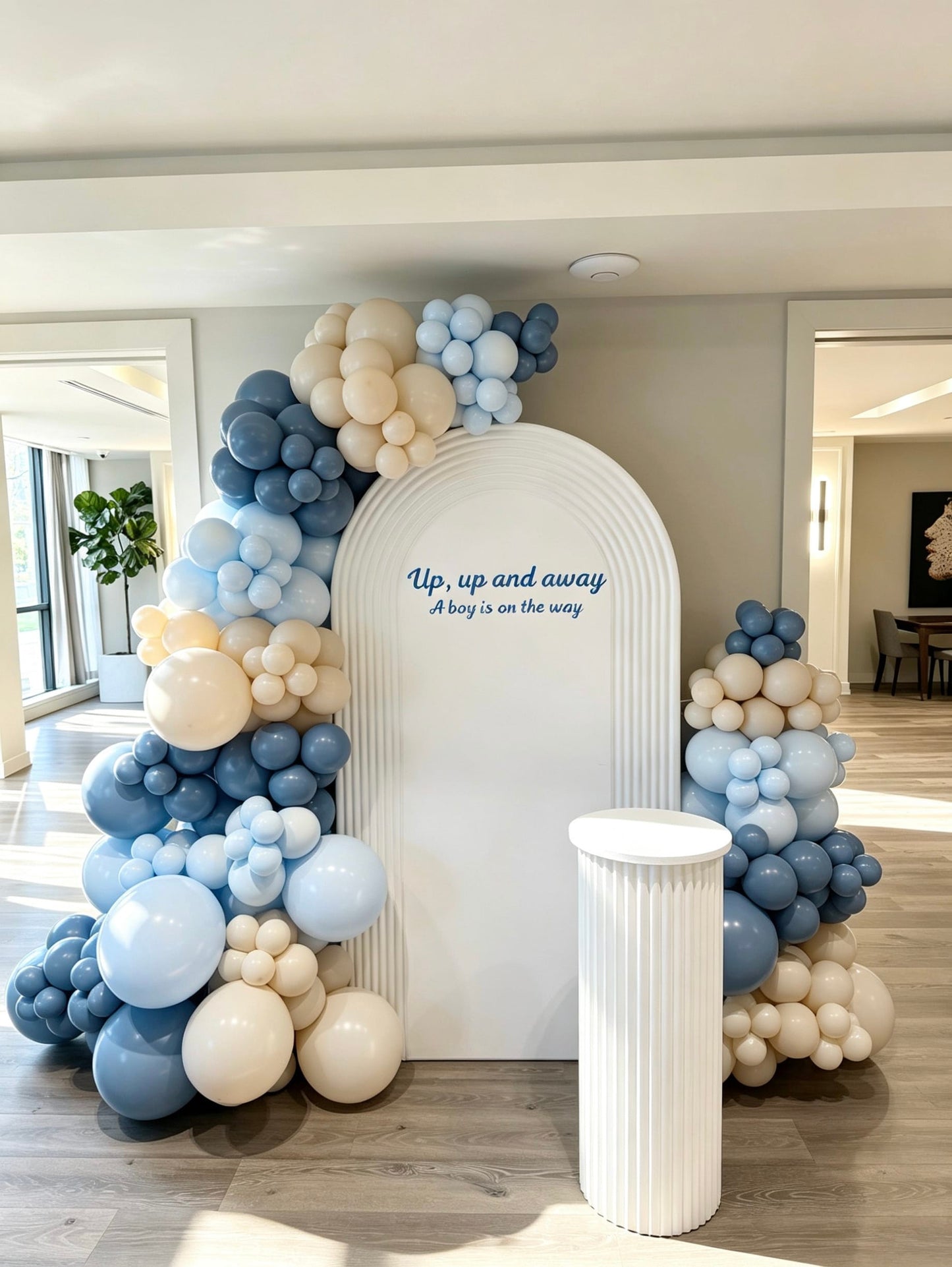 White ripple arch backdrop with blue, ivory and cream balloon garlands and matching cake pedestal for a baby boy shower
