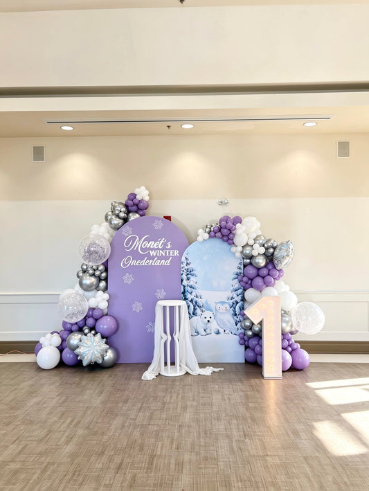 snowy one birthday backdrop with lavender balloon garlands and marquee number