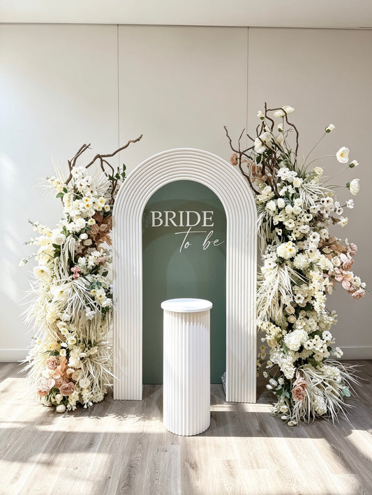 luxury bridal shower setup with white hollow ripple arch and elegant neutral floral installations