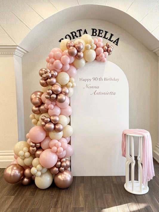90th birthday backdrop with blush pink and rose gold balloon garland and white full arch backdrop