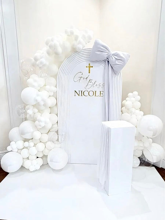 White Communion balloon backdrop with ripple arch panel, oversized bow and organic balloon garlands