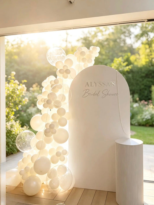 White bridal shower arch backdrop with organic white balloons, clear bubble balloons, pearl accents and ribbed pedestal
